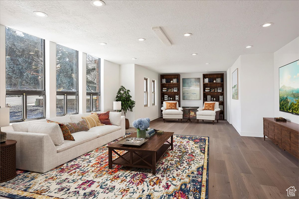 Living room with a wall of windows, wood finished floors, a textured ceiling, and recessed lighting