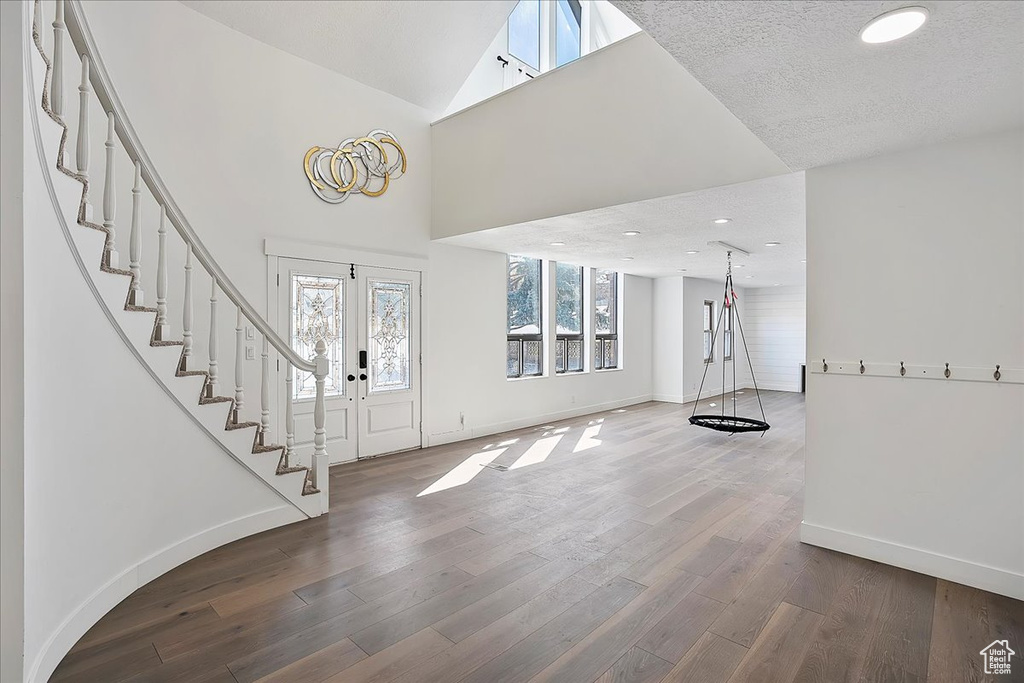 Foyer entrance with baseboards, wood finished floors, stairs, high vaulted ceiling, and recessed lighting