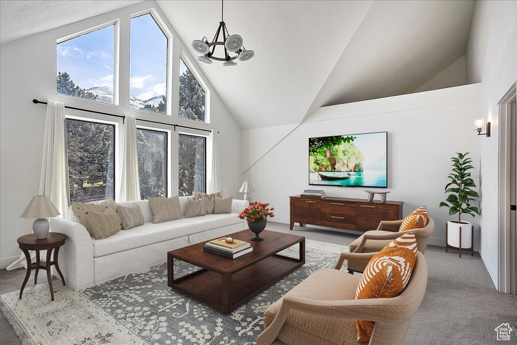 Carpeted living area with plenty of natural light, baseboards, high vaulted ceiling, and a notable chandelier