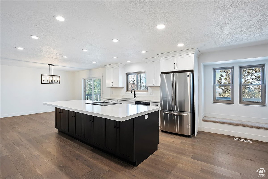 Kitchen featuring visible vents, dark wood-style flooring, freestanding refrigerator, light countertops, and white cabinetry