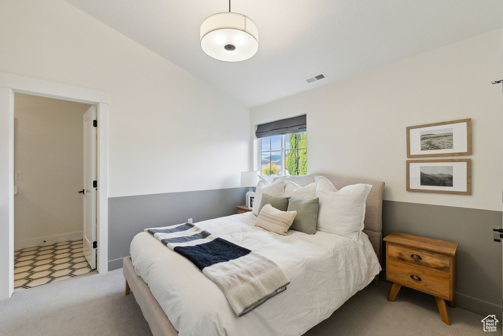 Bedroom with lofted ceiling, carpet floors, visible vents, and baseboards