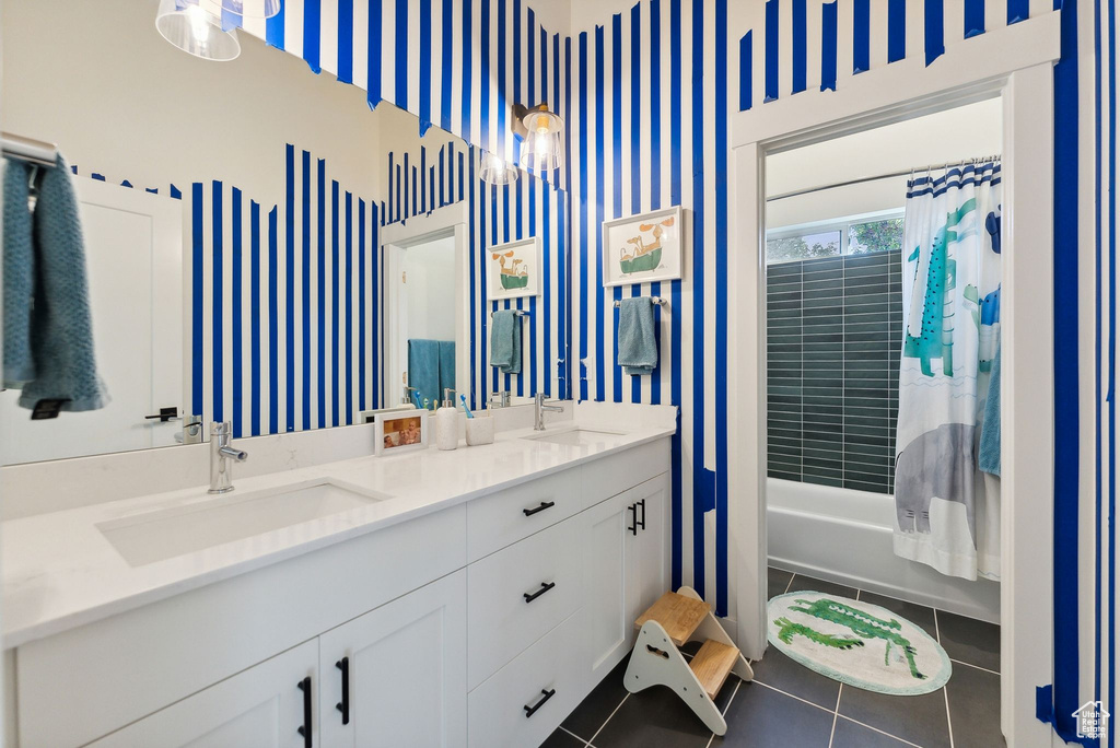 Bathroom featuring double vanity, wallpapered walls, a sink, and tile patterned floors