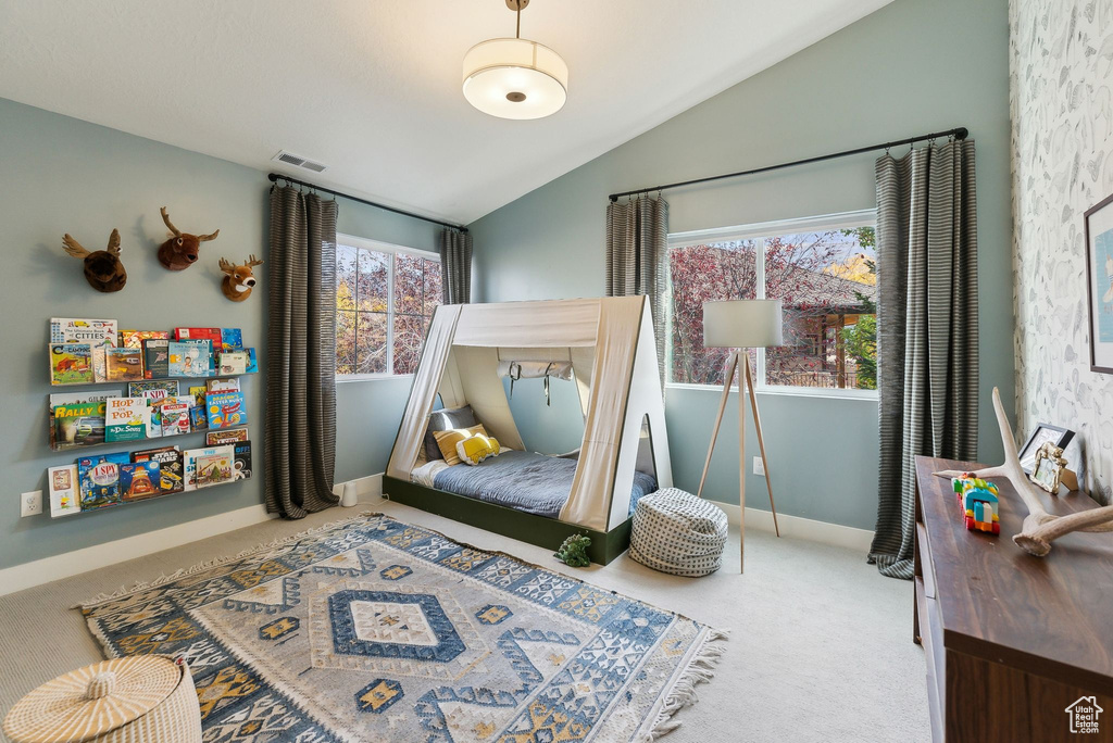 Carpeted bedroom with baseboards, visible vents, and vaulted ceiling