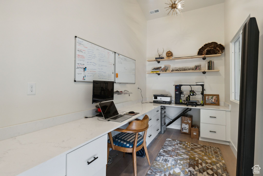 Home office featuring built in desk, wood finished floors, and visible vents
