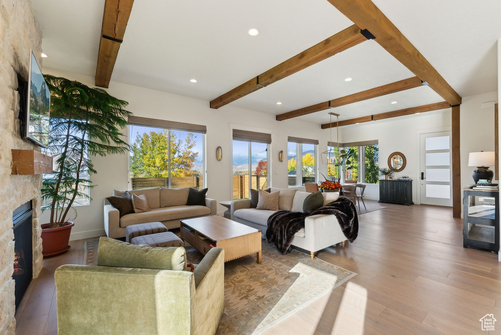 Living room featuring light wood finished floors, a fireplace, beamed ceiling, and recessed lighting