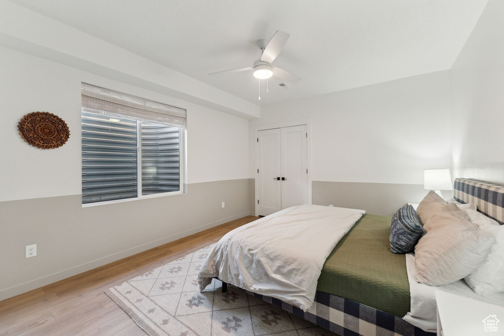 Bedroom with a ceiling fan, a closet, light wood-style flooring, and baseboards