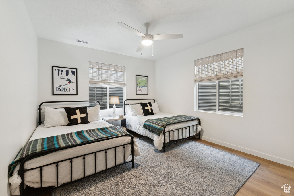 Bedroom featuring a ceiling fan, visible vents, baseboards, and wood finished floors