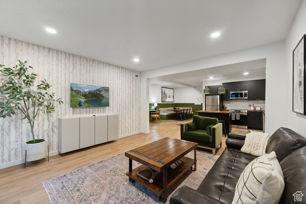 Living area with light wood-style floors, recessed lighting, and wallpapered walls