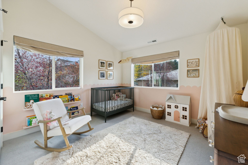 Interior space featuring vaulted ceiling, carpet flooring, visible vents, and baseboards