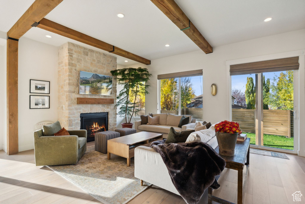 Living room featuring recessed lighting, beam ceiling, a fireplace, and light wood finished floors