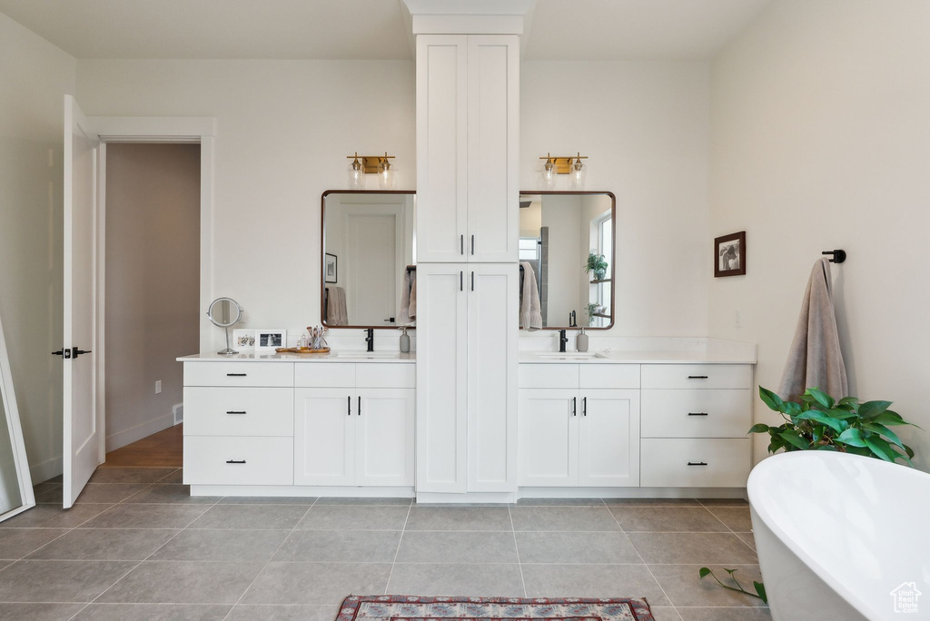 Bathroom featuring a soaking tub, two vanities, a sink, and tile patterned floors