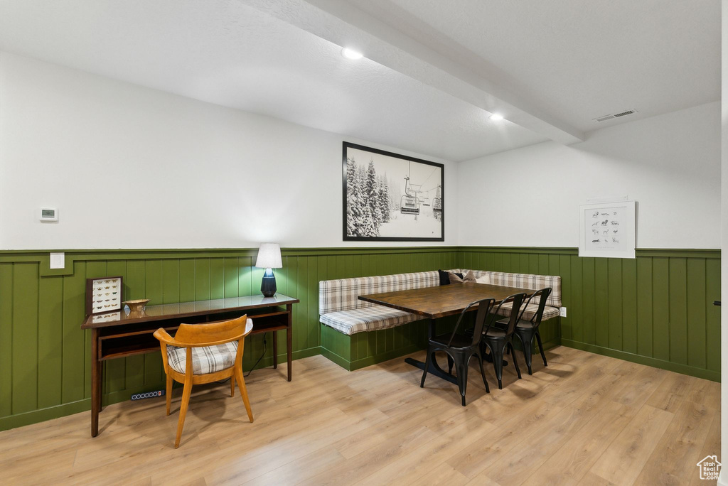 Dining area with a wainscoted wall, breakfast area, beamed ceiling, and wood finished floors