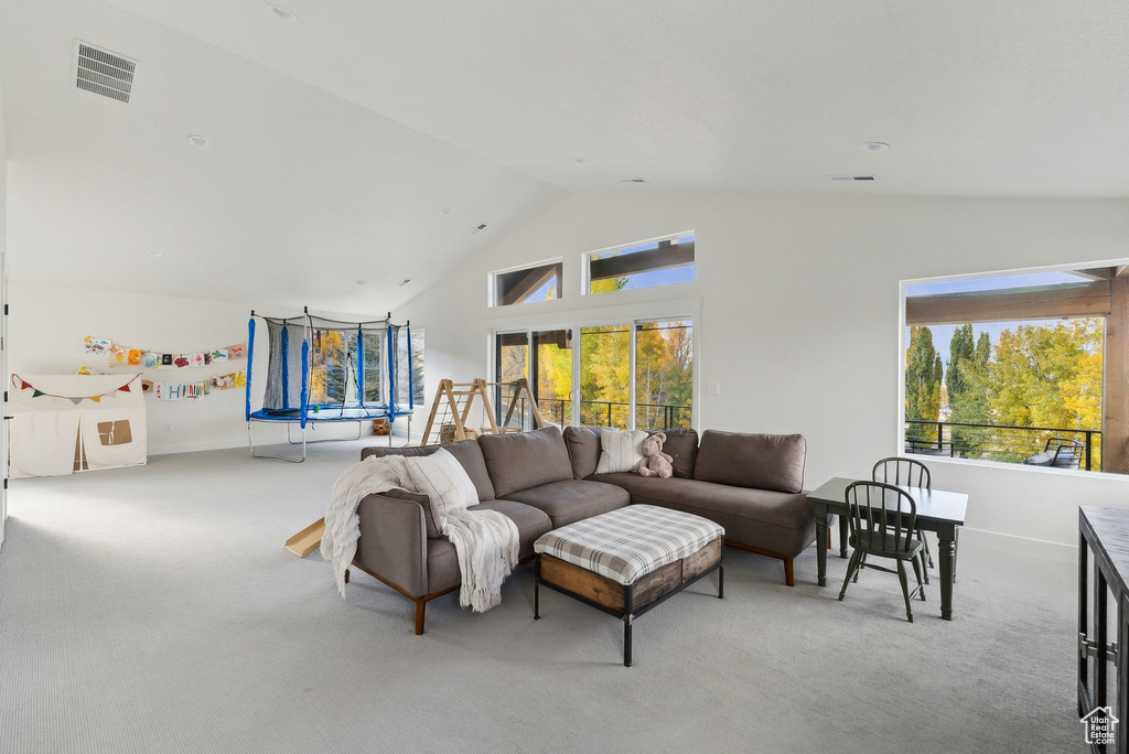 Carpeted living area with high vaulted ceiling, baseboards, and visible vents
