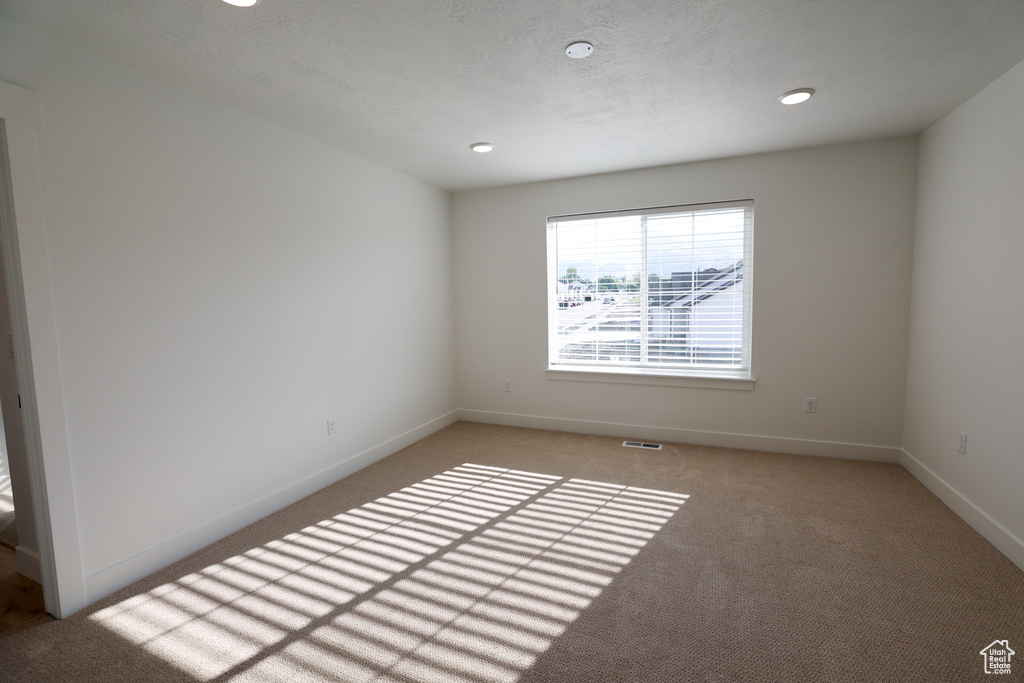 Unfurnished room featuring light colored carpet, visible vents, and baseboards