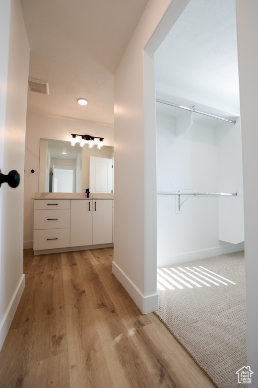 Bathroom featuring visible vents, baseboards, wood finished floors, and vanity