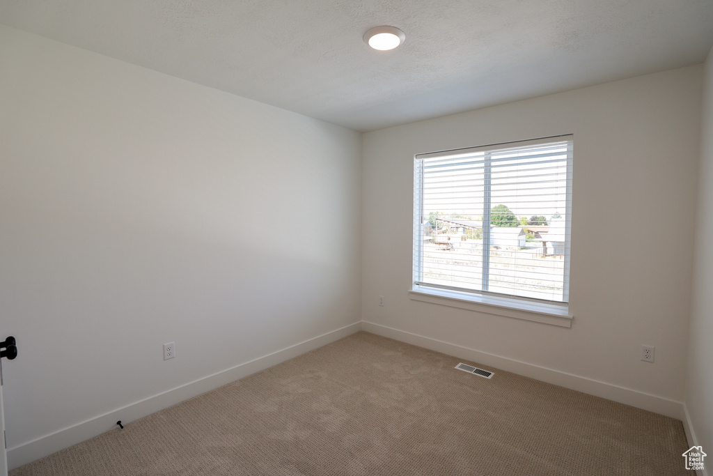 Empty room featuring light carpet, baseboards, and visible vents
