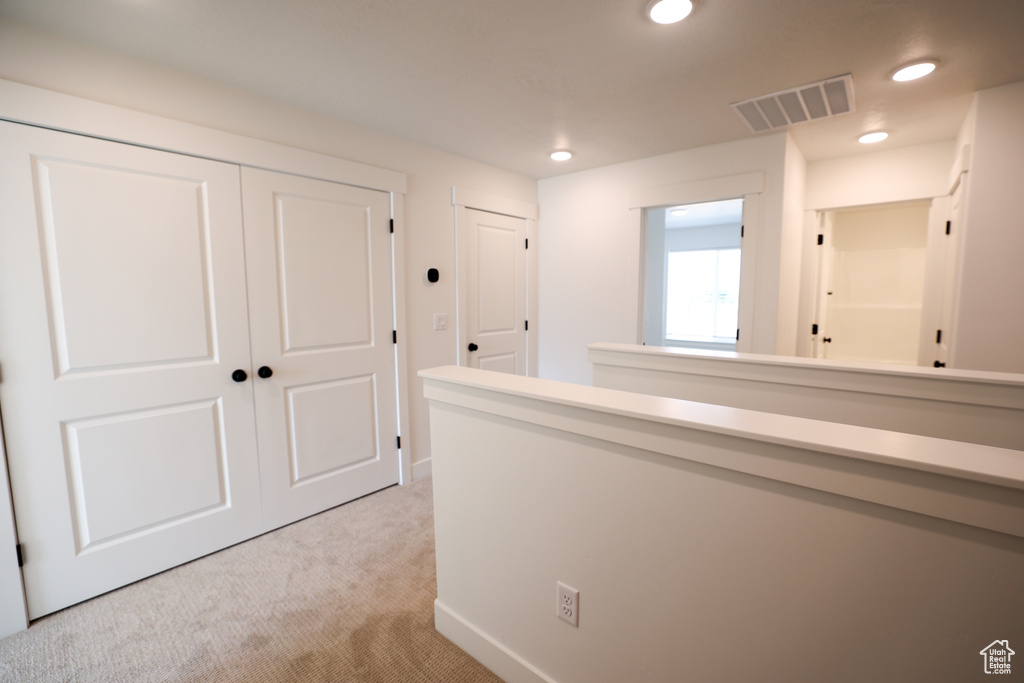 Hallway with light colored carpet, visible vents, baseboards, and recessed lighting