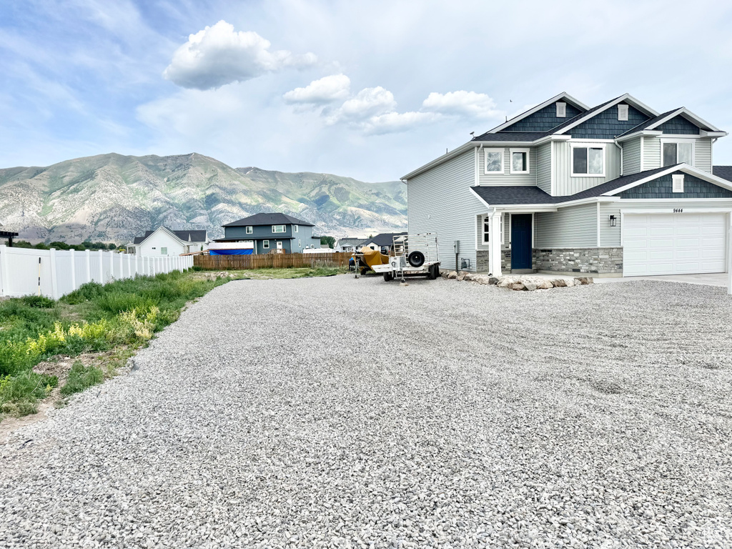 View of side of property featuring driveway, stone siding, and a mountain view