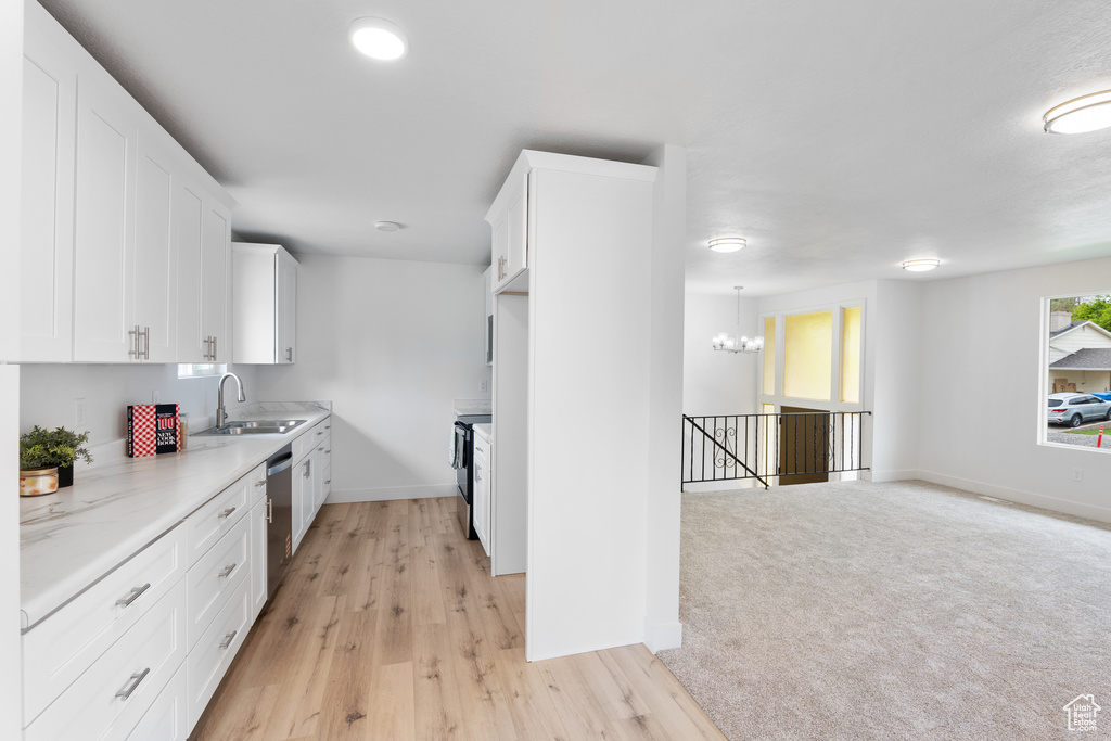 Kitchen with a sink, white cabinets, dishwasher, and baseboards