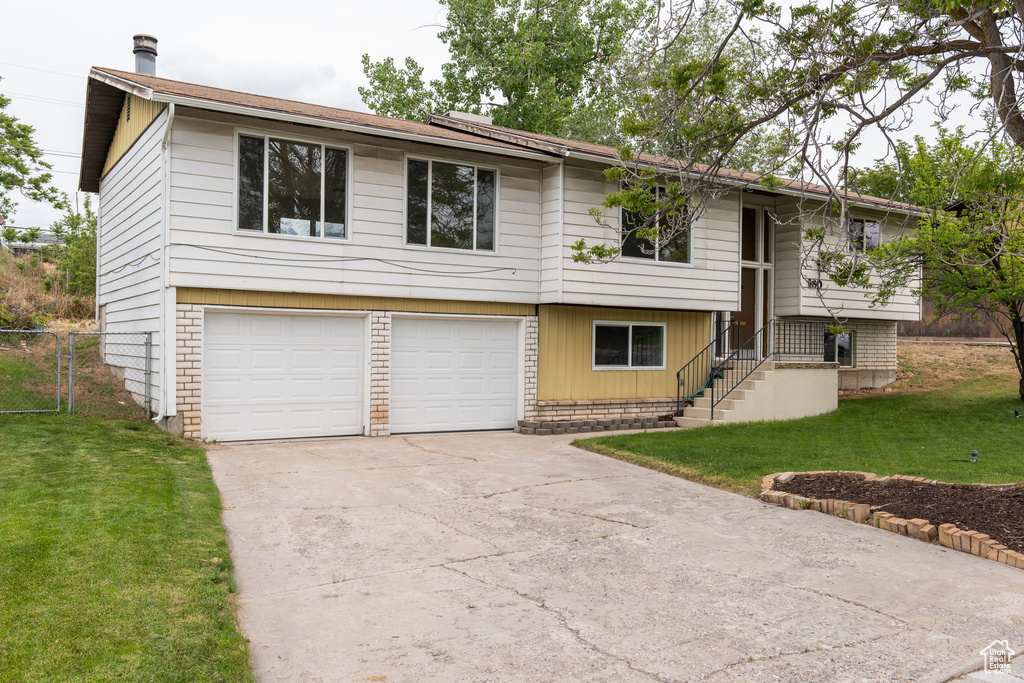 Split foyer home with concrete driveway and an attached garage