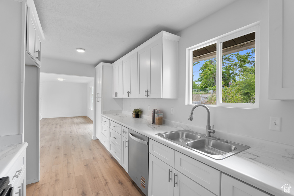Kitchen featuring stainless steel dishwasher, a sink, white cabinets, and light wood finished floors