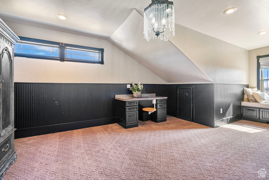 Home office with light colored carpet, a wealth of natural light, wainscoting, and lofted ceiling