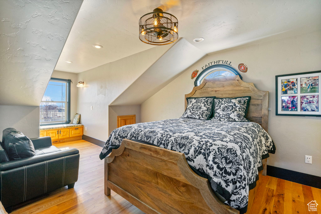 Bedroom featuring light wood-type flooring, lofted ceiling, and baseboards