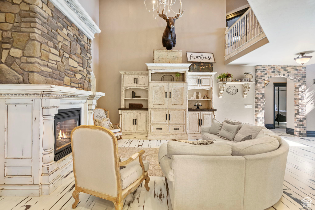 Living area with light wood-type flooring, a high ceiling, arched walkways, and a glass covered fireplace