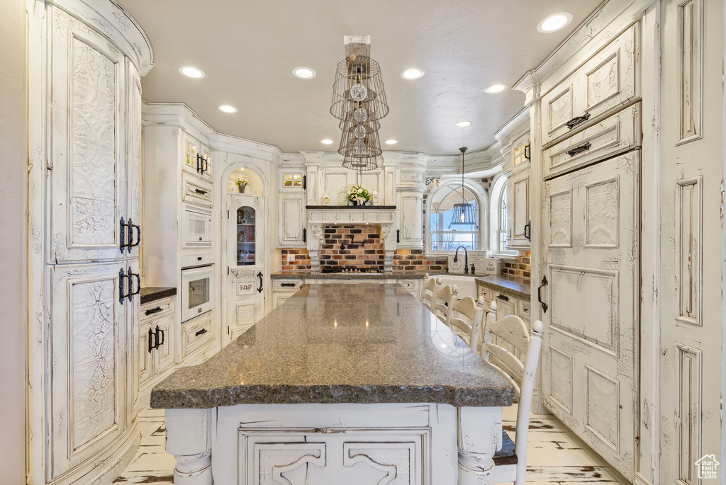 Kitchen featuring white appliances, tasteful backsplash, a kitchen island, decorative light fixtures, and recessed lighting