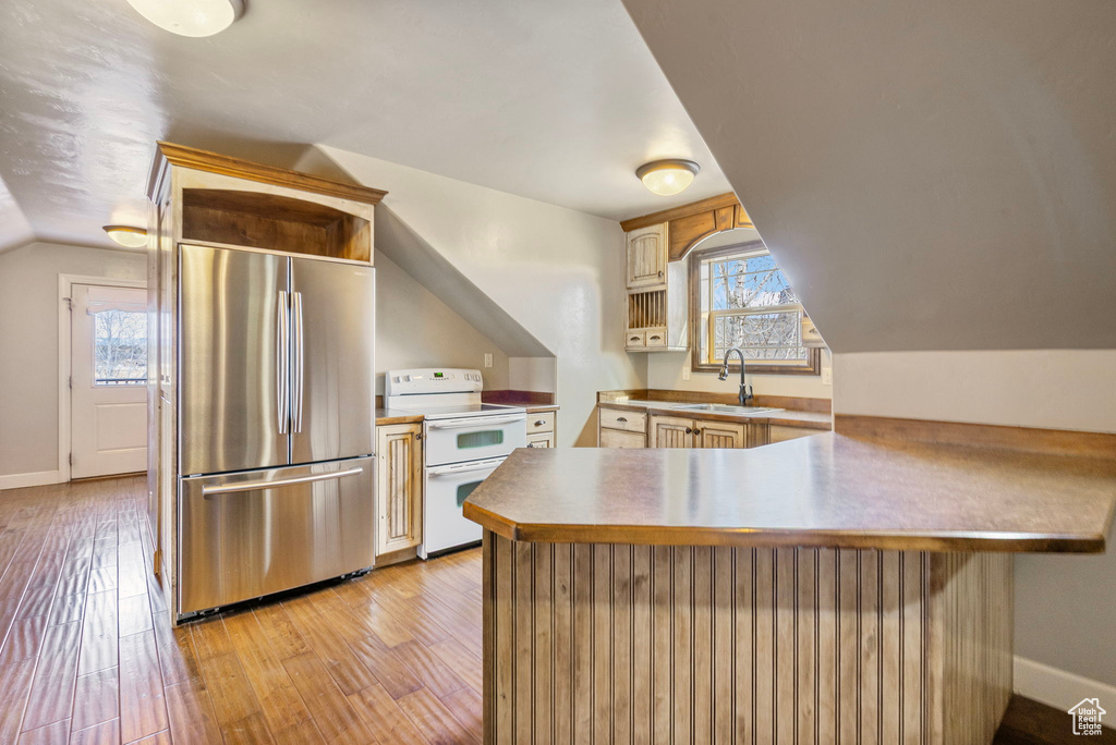 Kitchen featuring light wood finished floors, stainless steel refrigerator, a peninsula, double oven range, and a sink