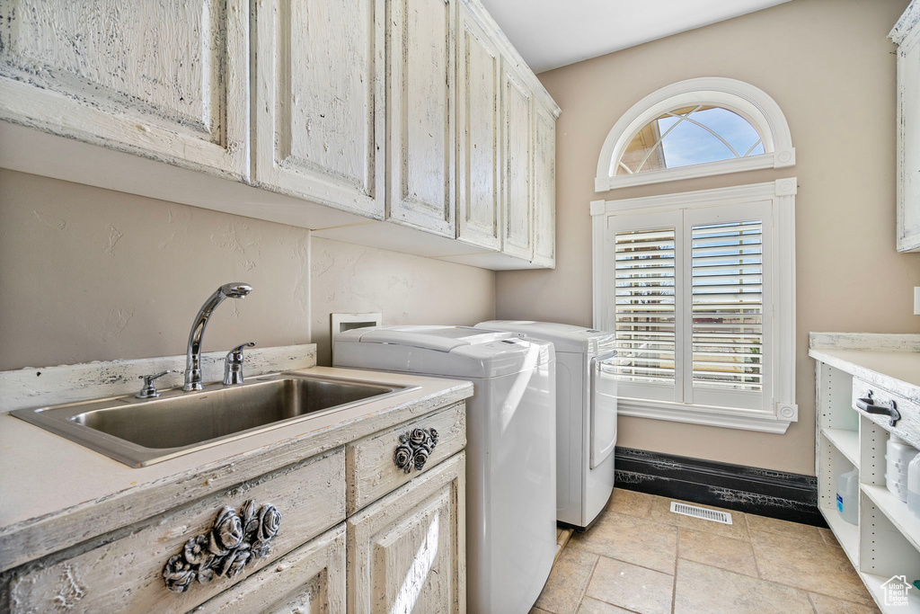 Washroom featuring separate washer and dryer, plenty of natural light, a sink, and cabinet space