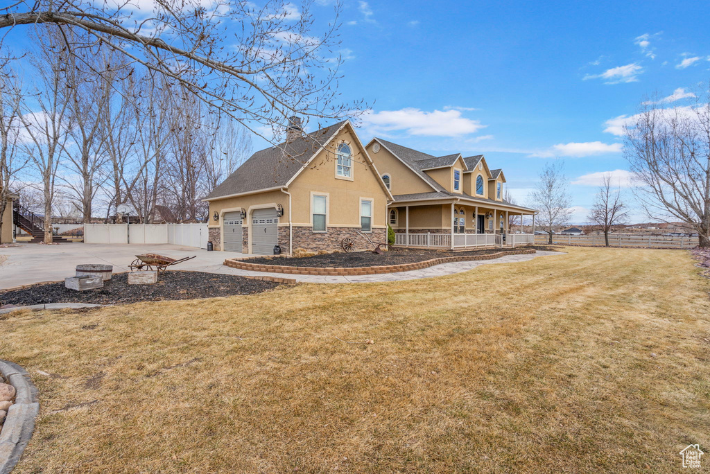 View of front of property featuring a garage, stone siding, fence, a porch, and stucco siding