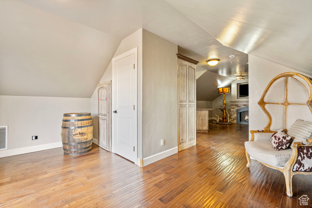 Additional living space with a lit fireplace, wood finished floors, visible vents, and baseboards