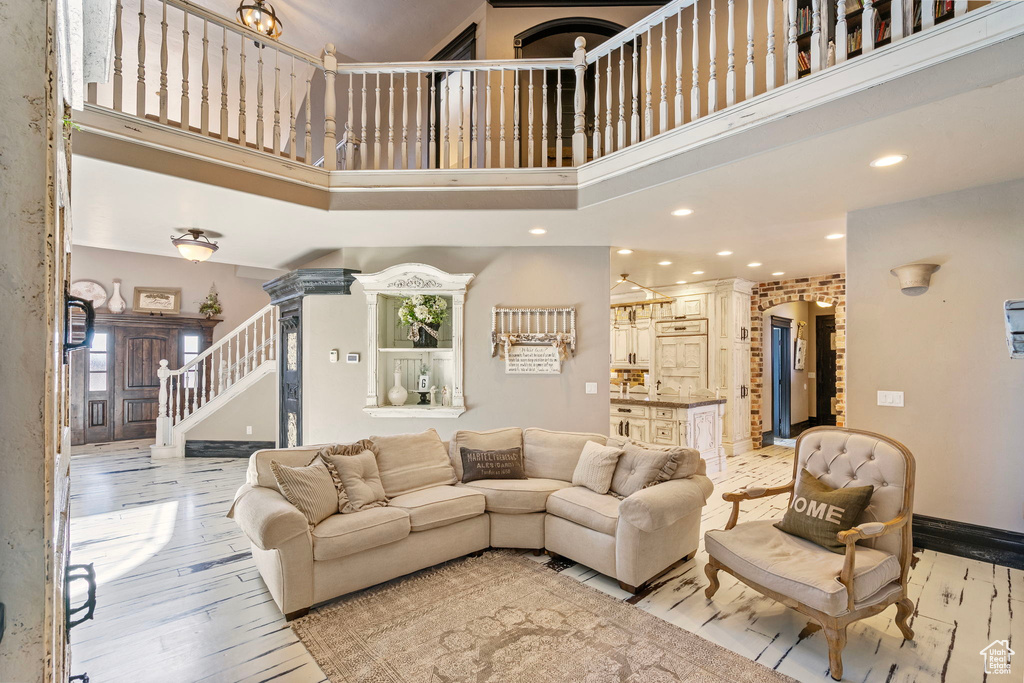 Living area featuring stairs, recessed lighting, a towering ceiling, and light wood-style floors