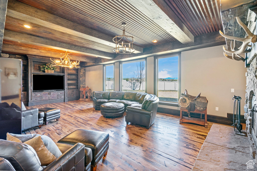 Living area featuring wood ceiling, wood-type flooring, a notable chandelier, a fireplace, and beam ceiling