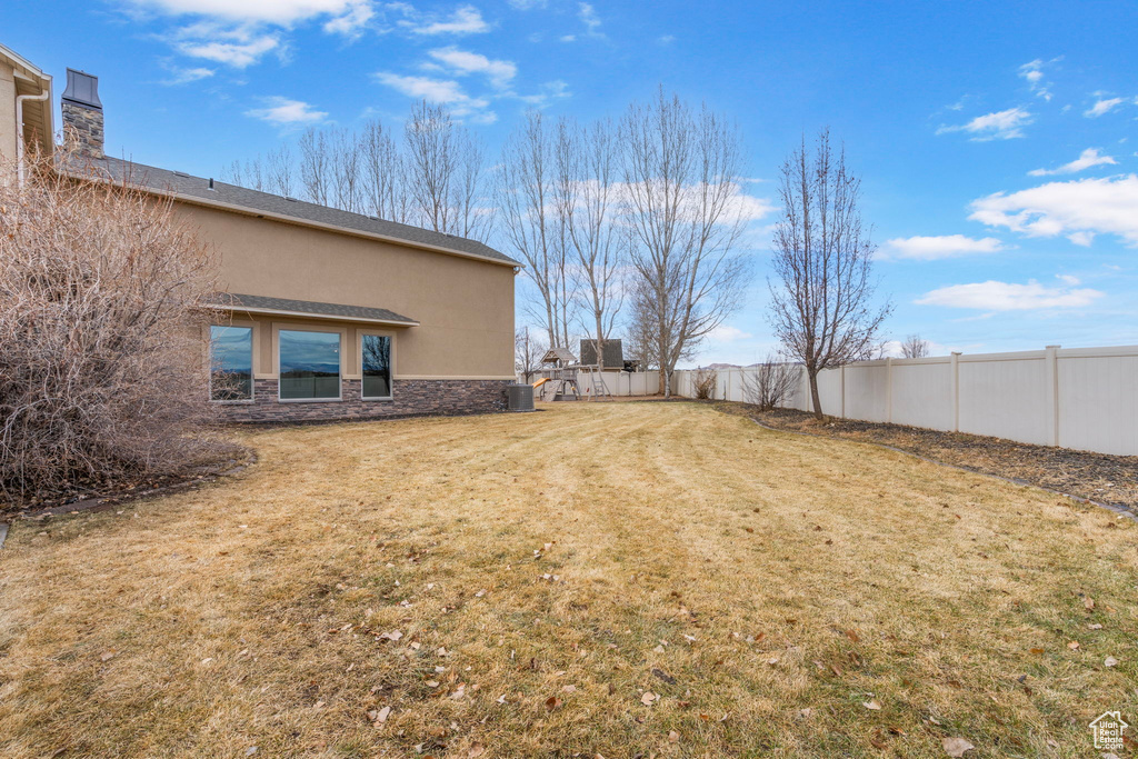 View of yard with central AC and fence