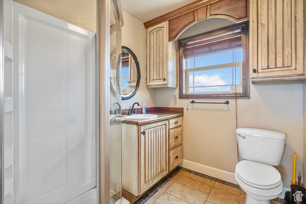 Full bathroom with toilet, tile patterned floors, baseboards, and vanity