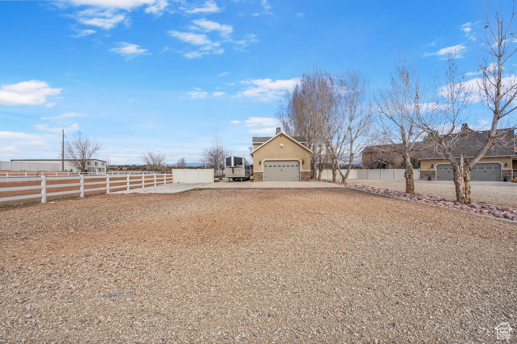 View of yard with a garage, fence, and driveway