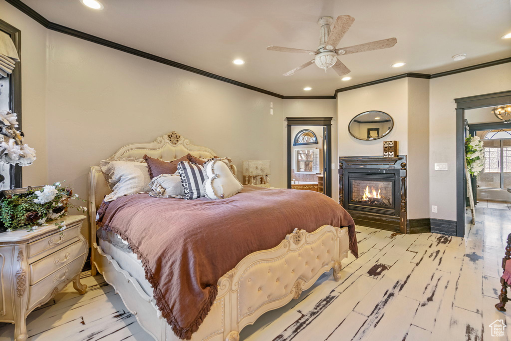 Bedroom with crown molding, recessed lighting, light wood-style flooring, a glass covered fireplace, and baseboards