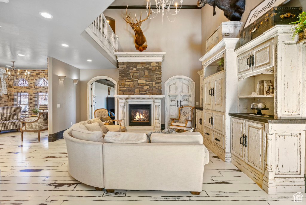 Living room featuring arched walkways, recessed lighting, light wood-style flooring, an inviting chandelier, and a glass covered fireplace