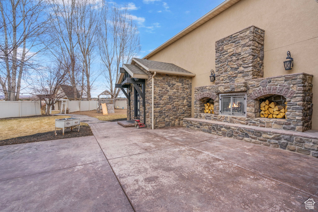 View of patio / terrace with an outdoor stone fireplace and fence