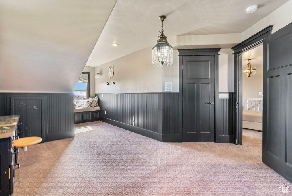 Interior space featuring wainscoting, carpet flooring, and an inviting chandelier