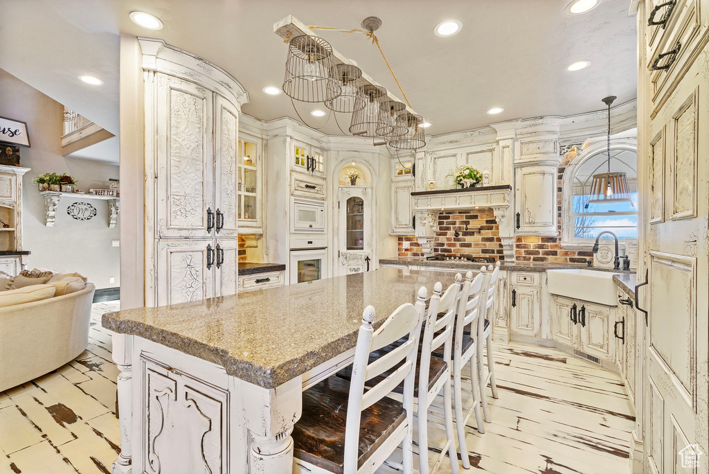 Kitchen featuring white microwave, recessed lighting, a kitchen island, a sink, and decorative backsplash