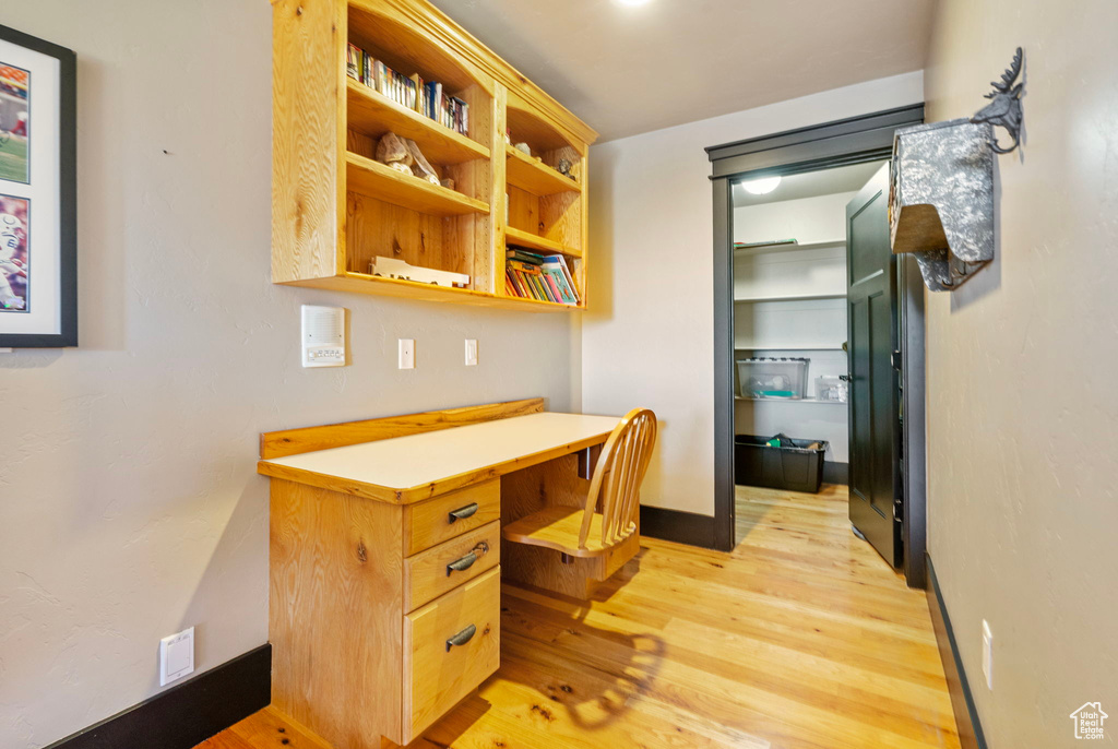 Office featuring light wood finished floors, built in desk, and baseboards