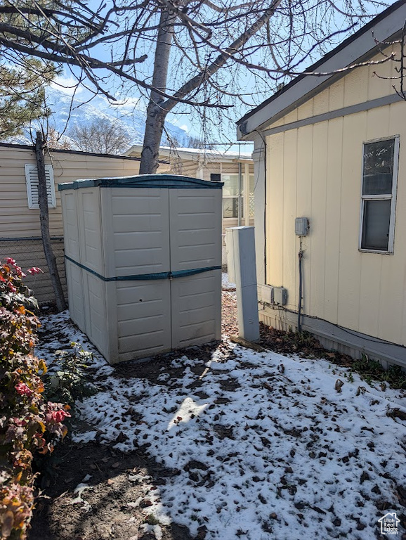 Snow covered structure featuring an outbuilding and a storage shed