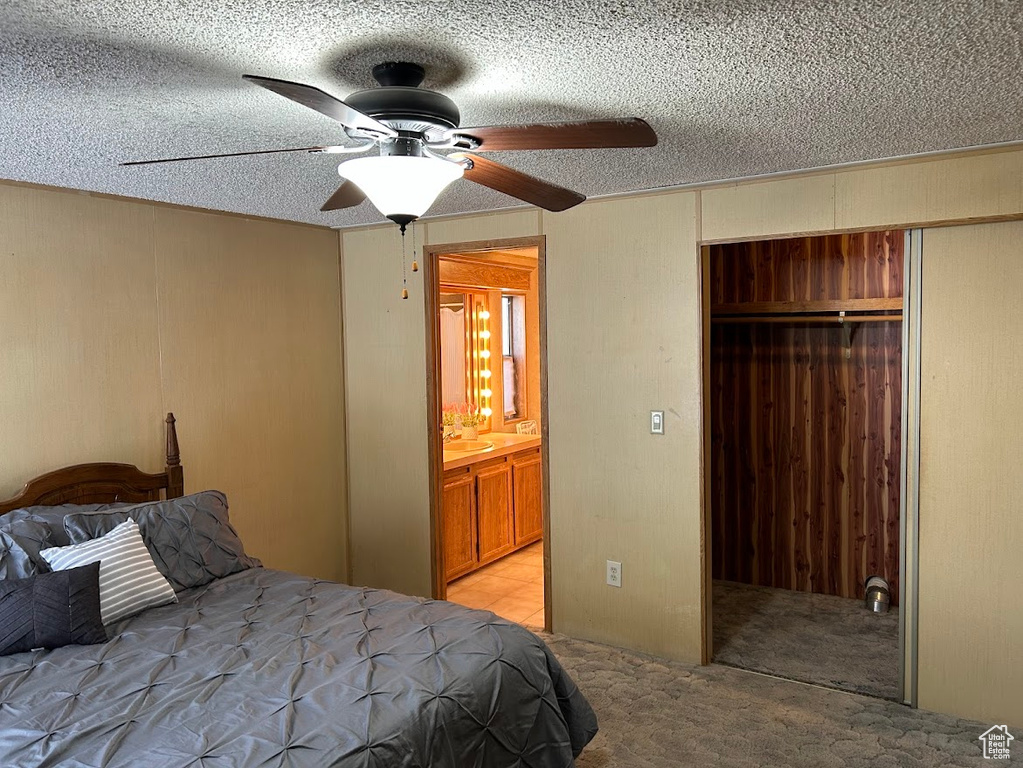 Bedroom with light carpet, wood walls, a closet, and a textured ceiling