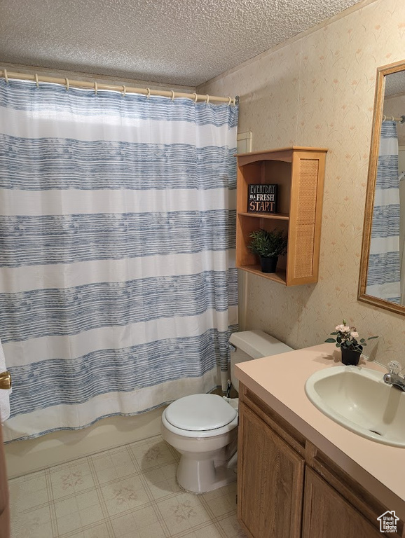 Full bathroom featuring a textured ceiling, toilet, vanity, wallpapered walls, and shower / bathtub combination with curtain