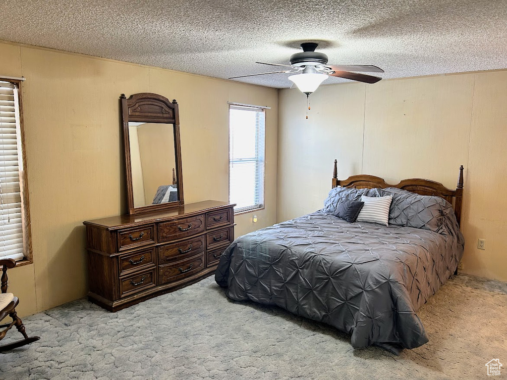 Carpeted bedroom featuring a ceiling fan and a textured ceiling