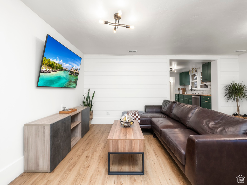 Living area with baseboards, light wood finished floors, visible vents, and wet bar