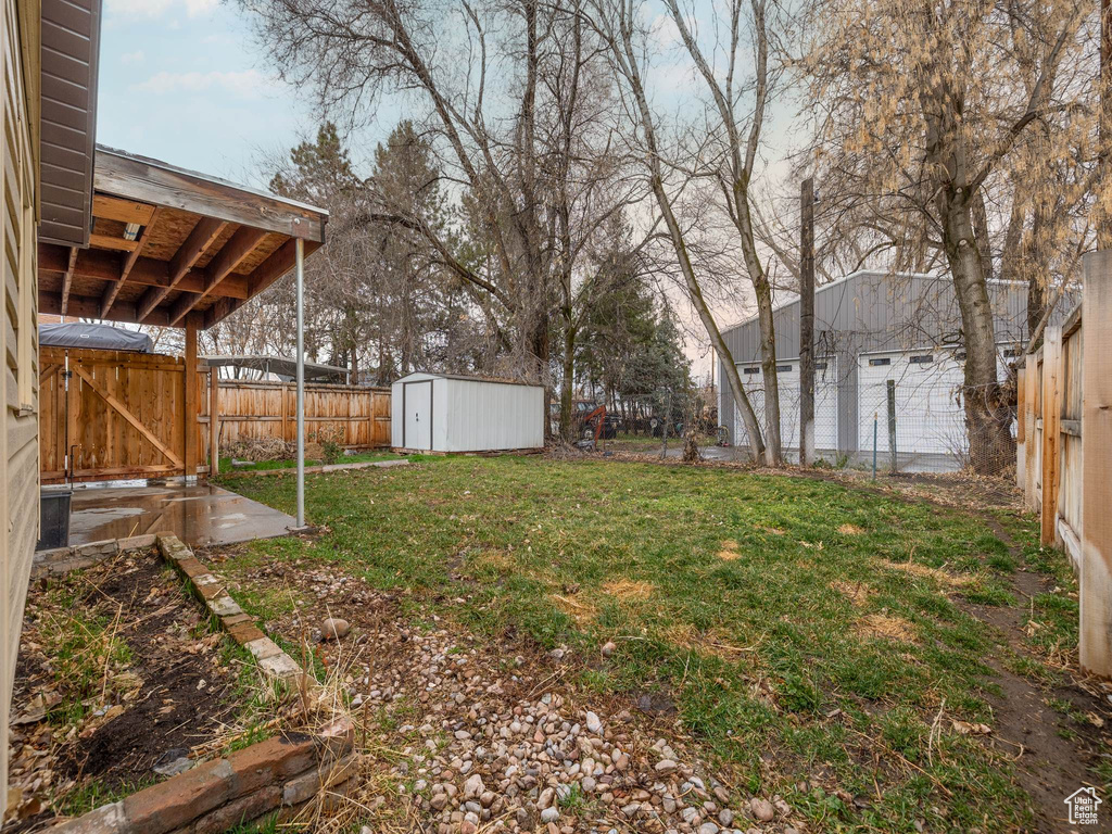 View of yard with an outbuilding, a gate, a fenced backyard, and a storage shed